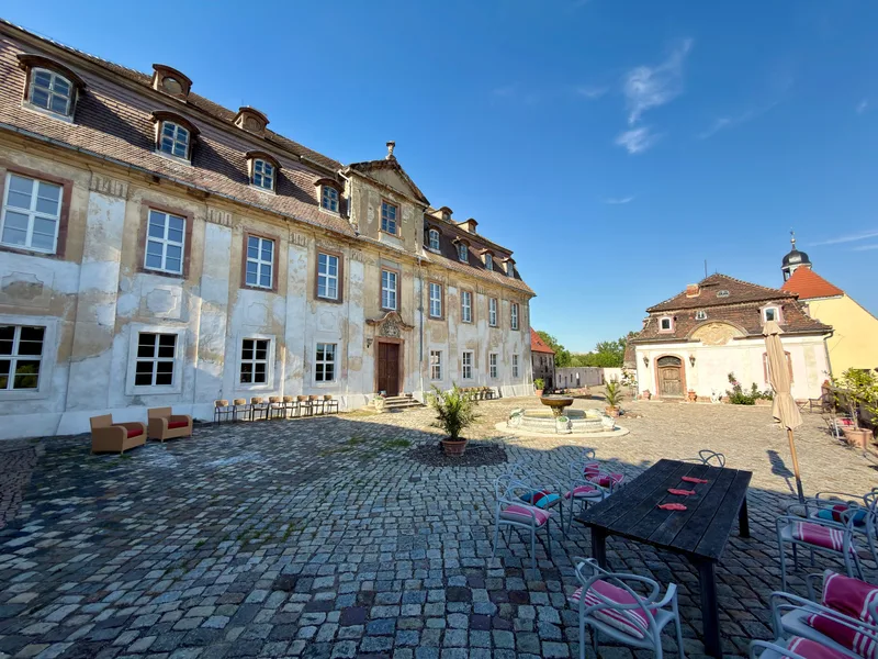 Schlossterrasse im Schlosshof von Schloss Bündorf mit Sitzplätzen in der Sonne