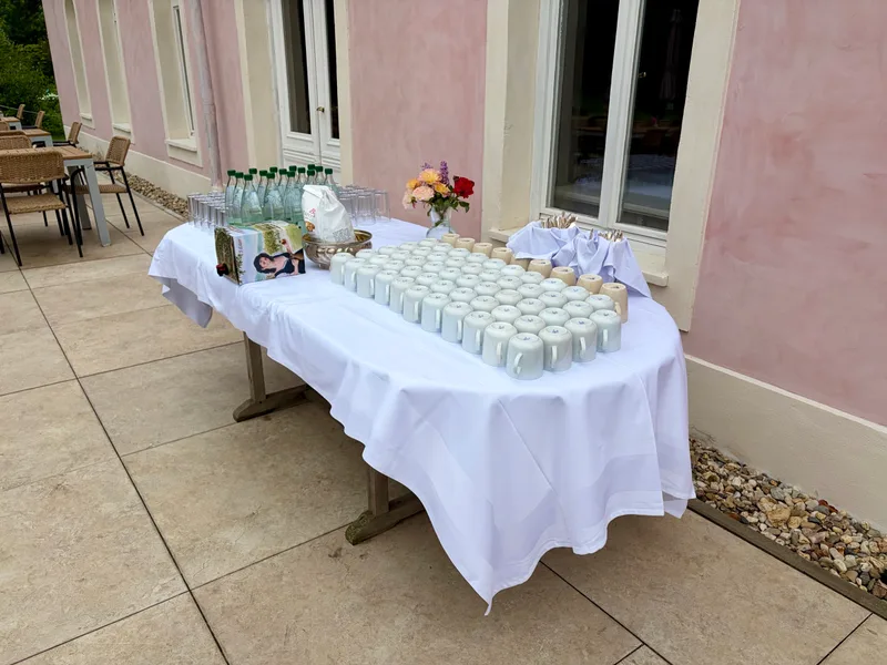 Kaffeestation mit Tassen, Wasser und Gebäck auf der Terrasse am Haus im Park
