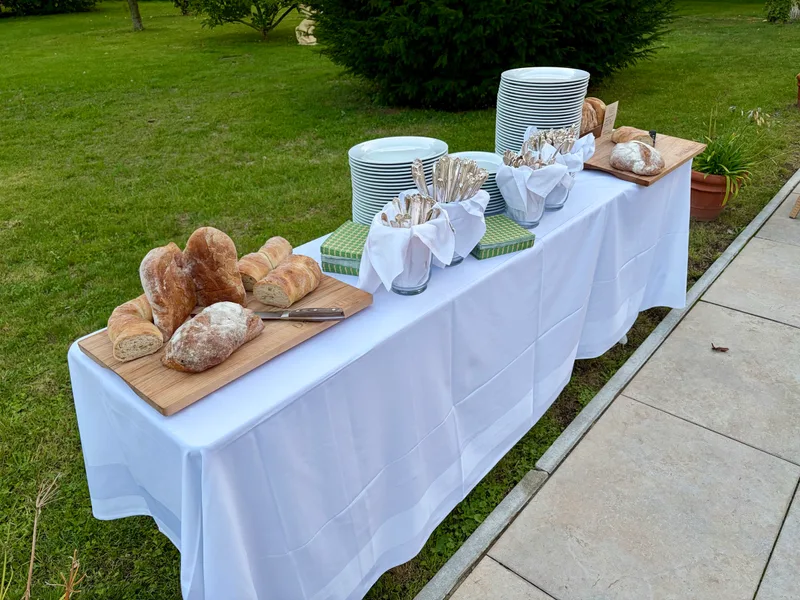 Buffet mit Brot, Tellern und Besteck auf der Terrasse am Haus im Park beim Firmenevent
