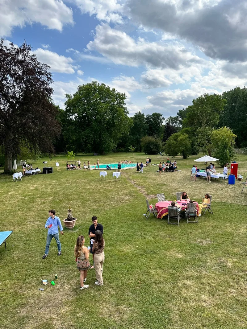 Sommerfest im Schlosspark von Schloss Bündorf mit Gästen auf der Wiese, Tischtennisplatte und Pool im Hintergrund