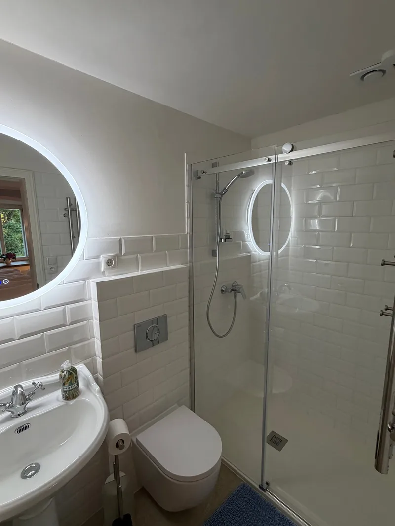 Helles Bad im Seezimmer mit weißen Metrofliesen, Glasdusche und beleuchtetem Spiegel, Schloss Bündorf